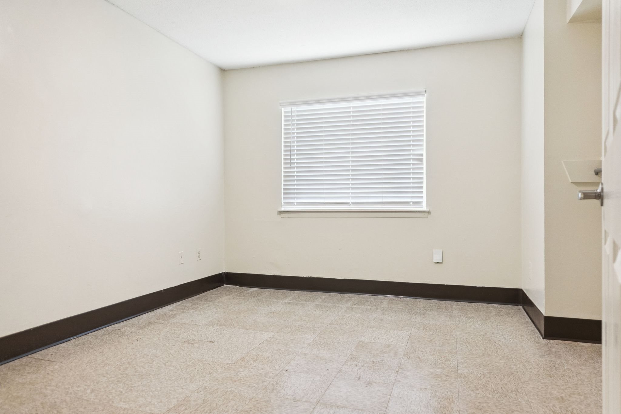 A room with a window covered by white blinds.